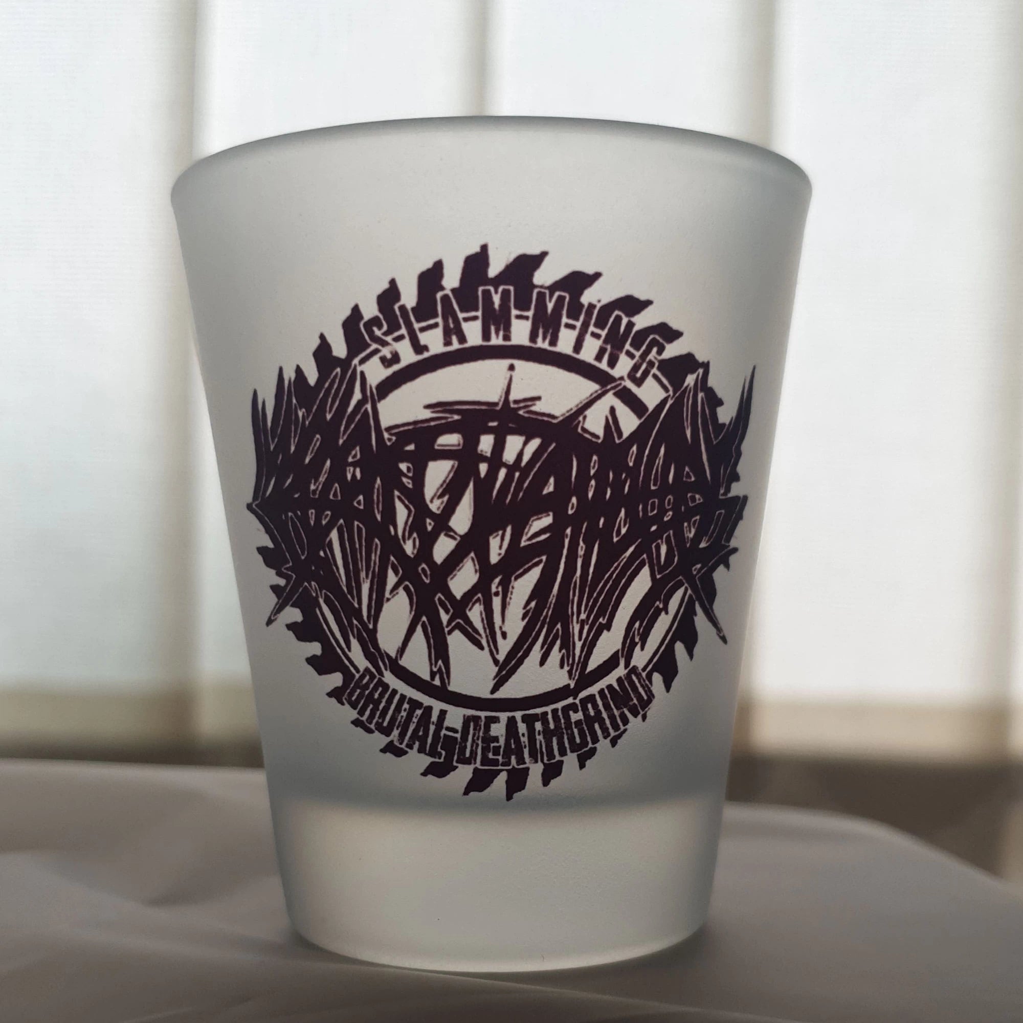 Frosted glass with a black band logo and text on a white surface