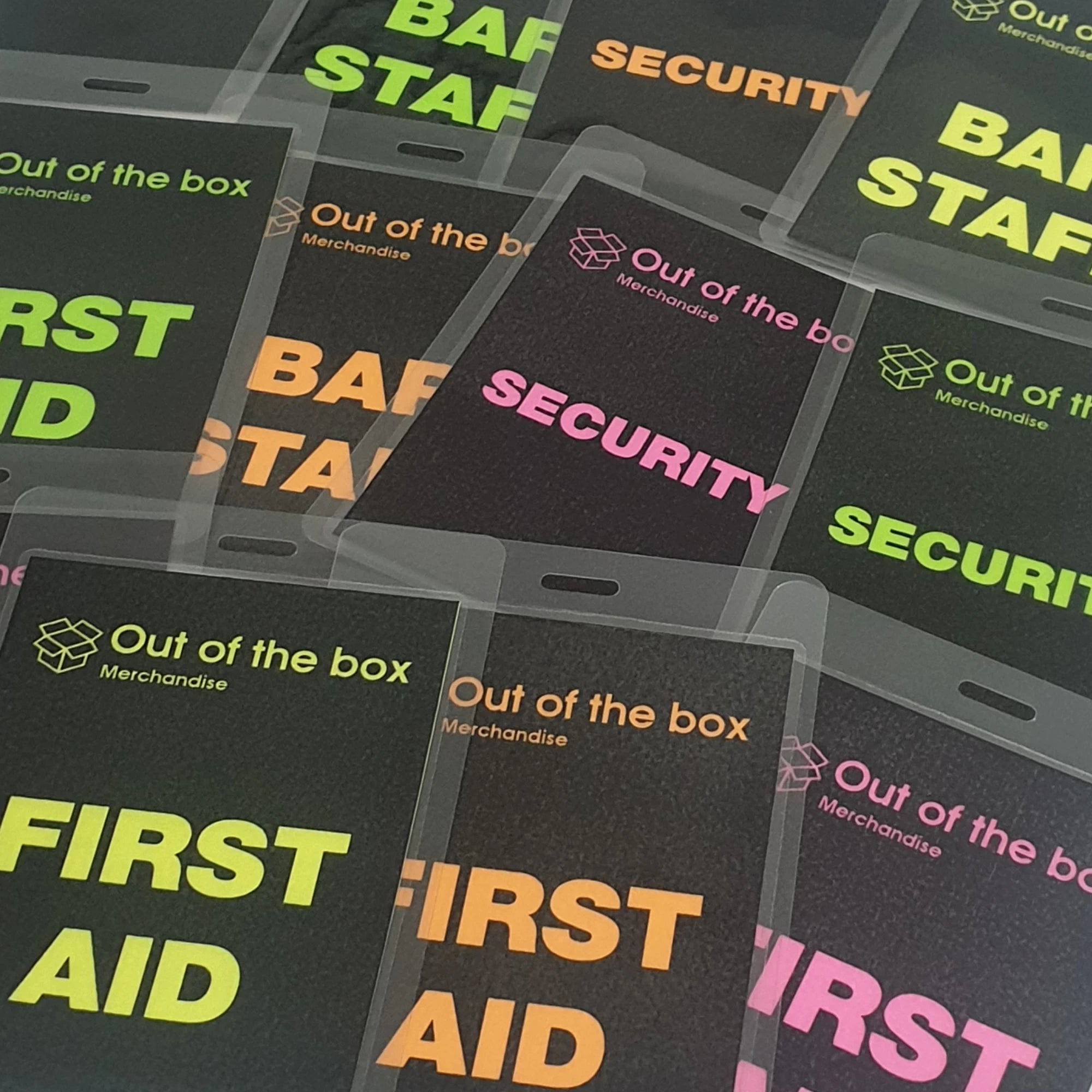 Collection of neon name badges with text like 'Bar Staff', 'Security', and 'First Aid' on a black background.