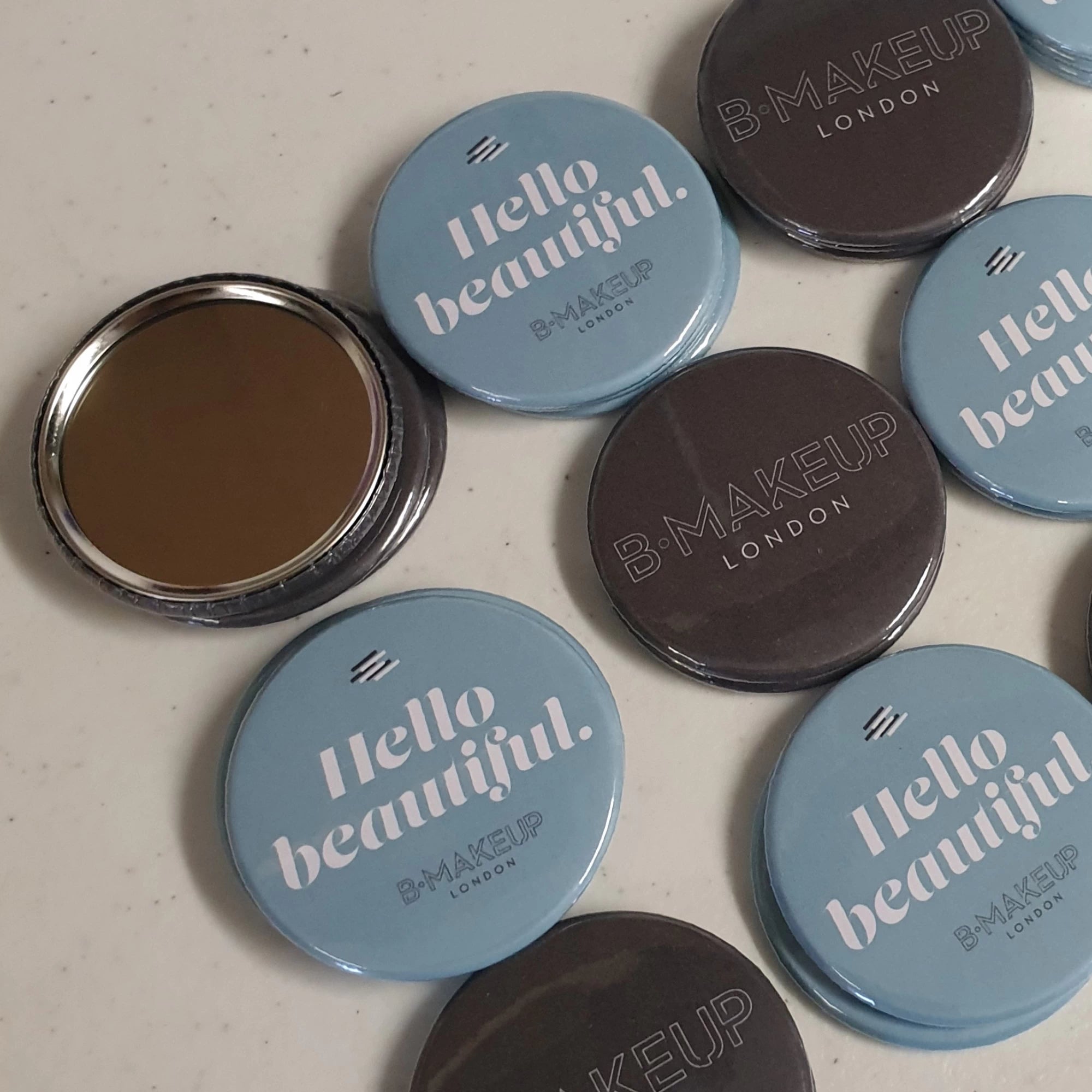 Makeup product with 'Hello Beautiful' and 'B Makeup London' branding on lids.