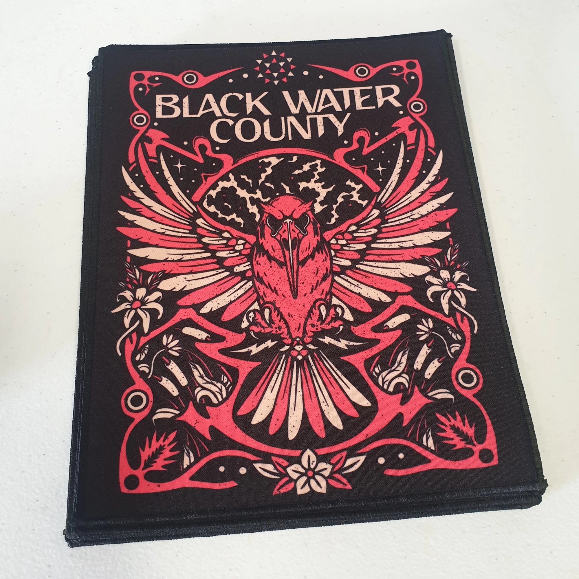 Back patch 'Black Water County' with a red and beige design on a white background