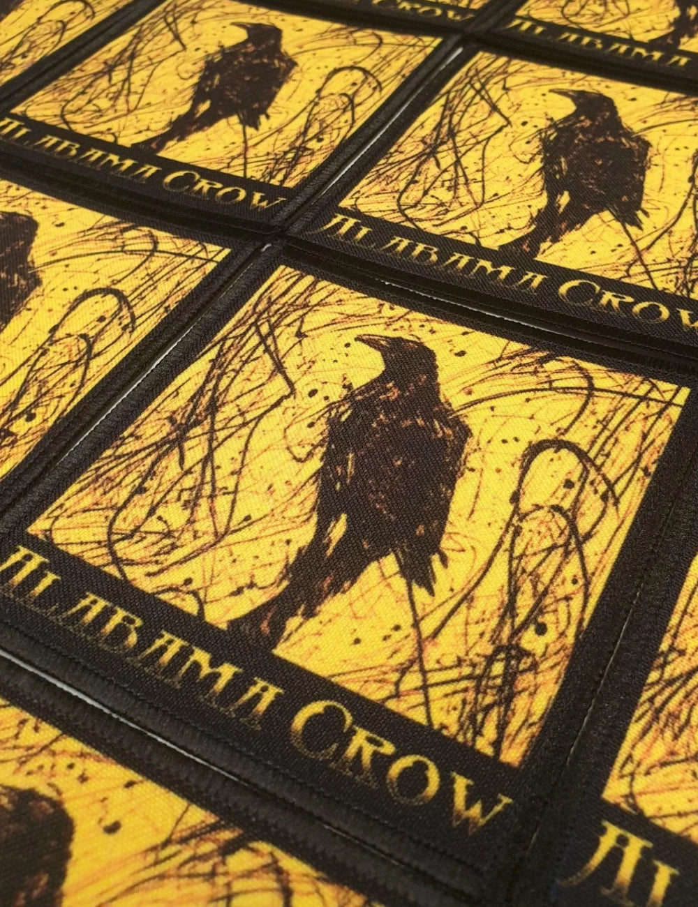 Custom band merchandise square patches, with a black crow and yellow background.