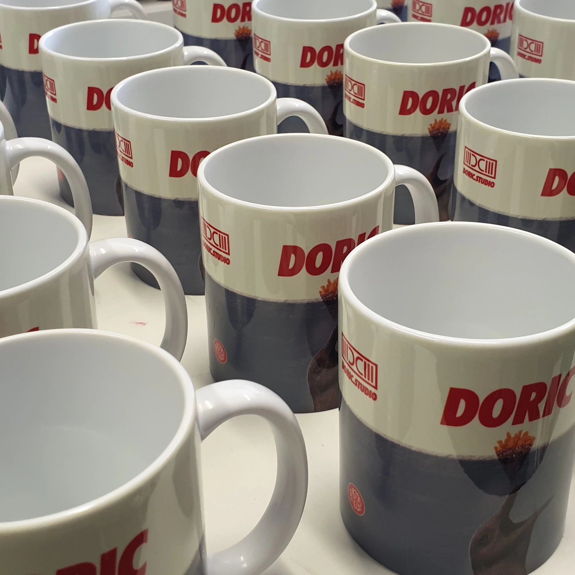 Multiple Doric studio mugs with visible branding on a surface.