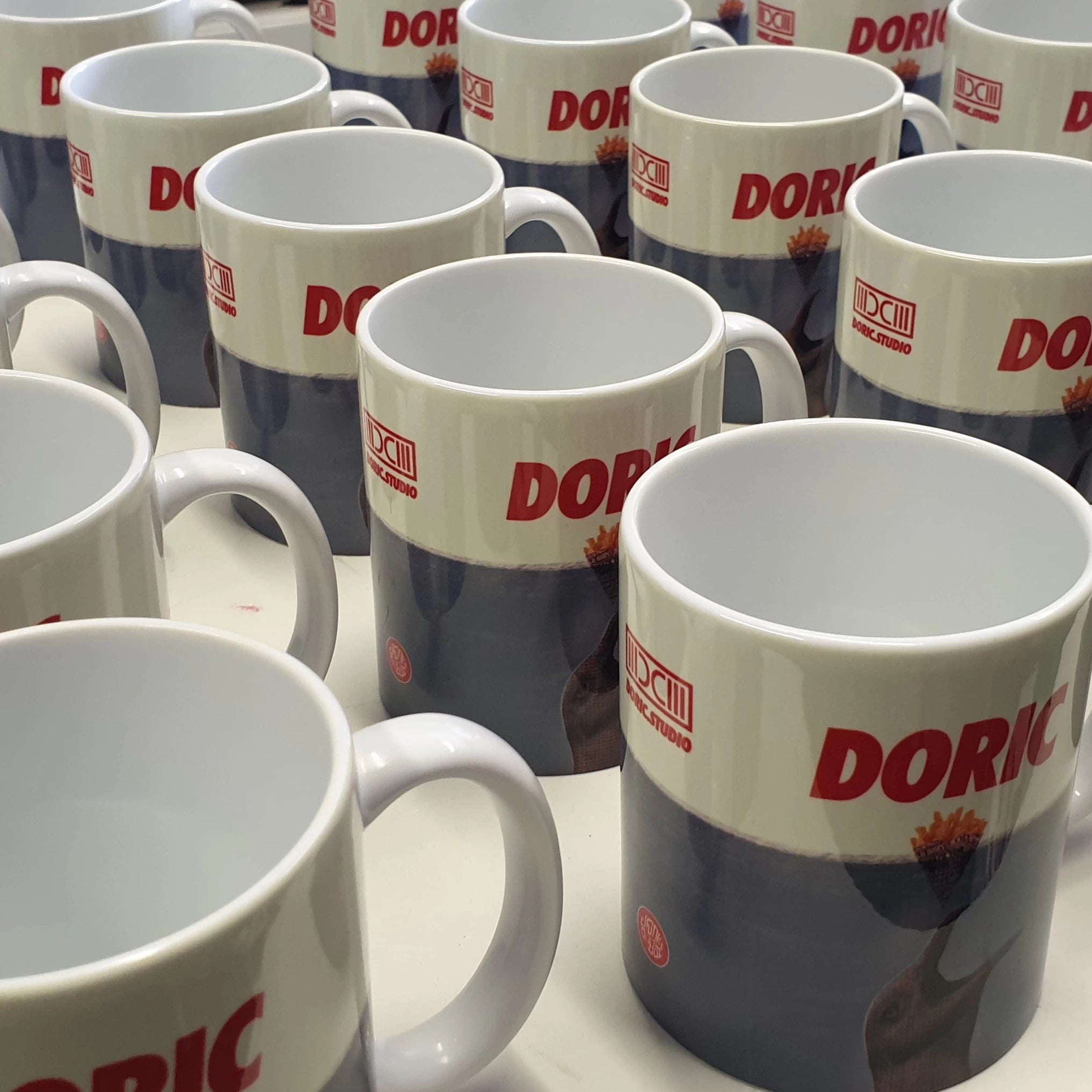 Multiple Doric mugs with red and blue design on a white surface
