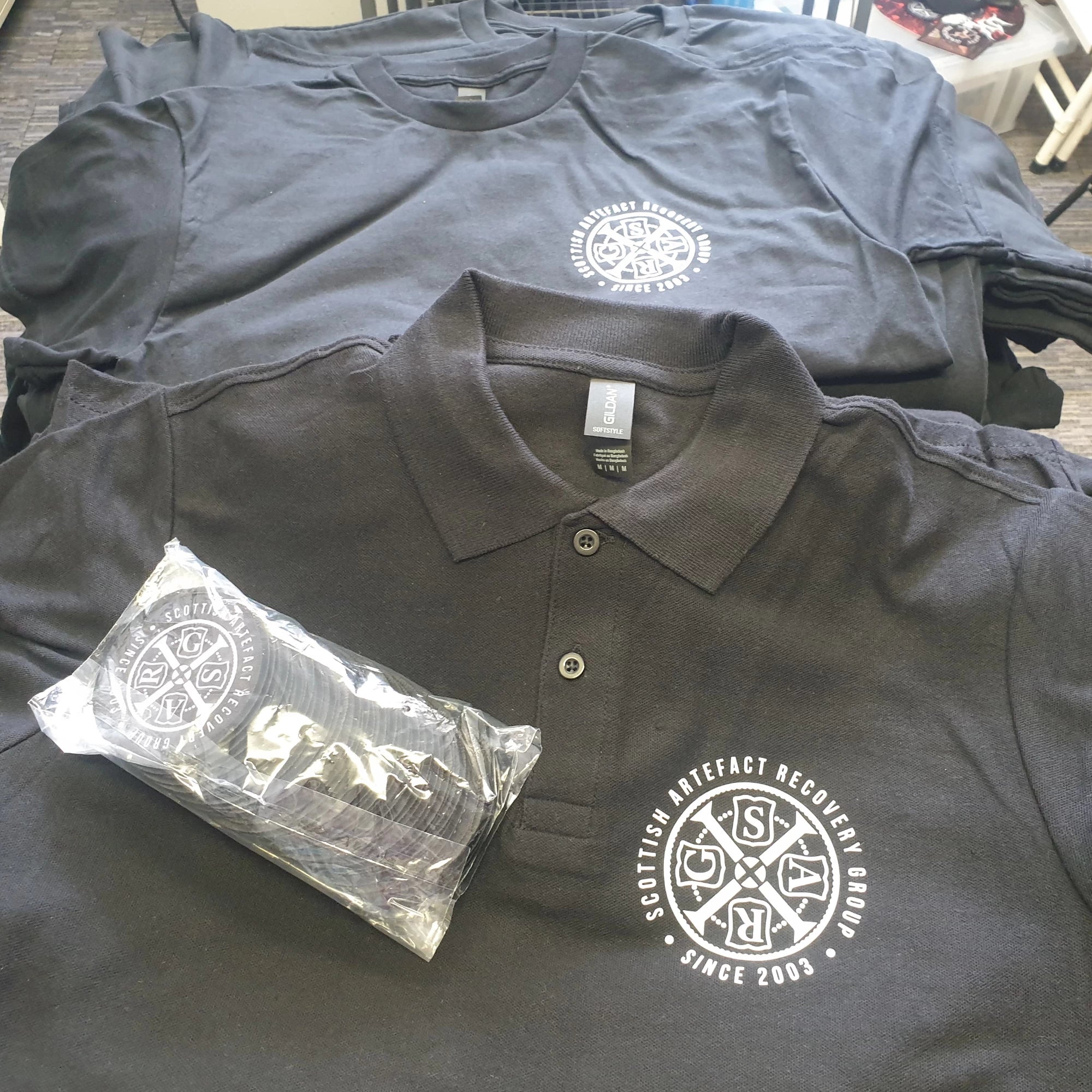 Black polo shirts with SARG logo on a table