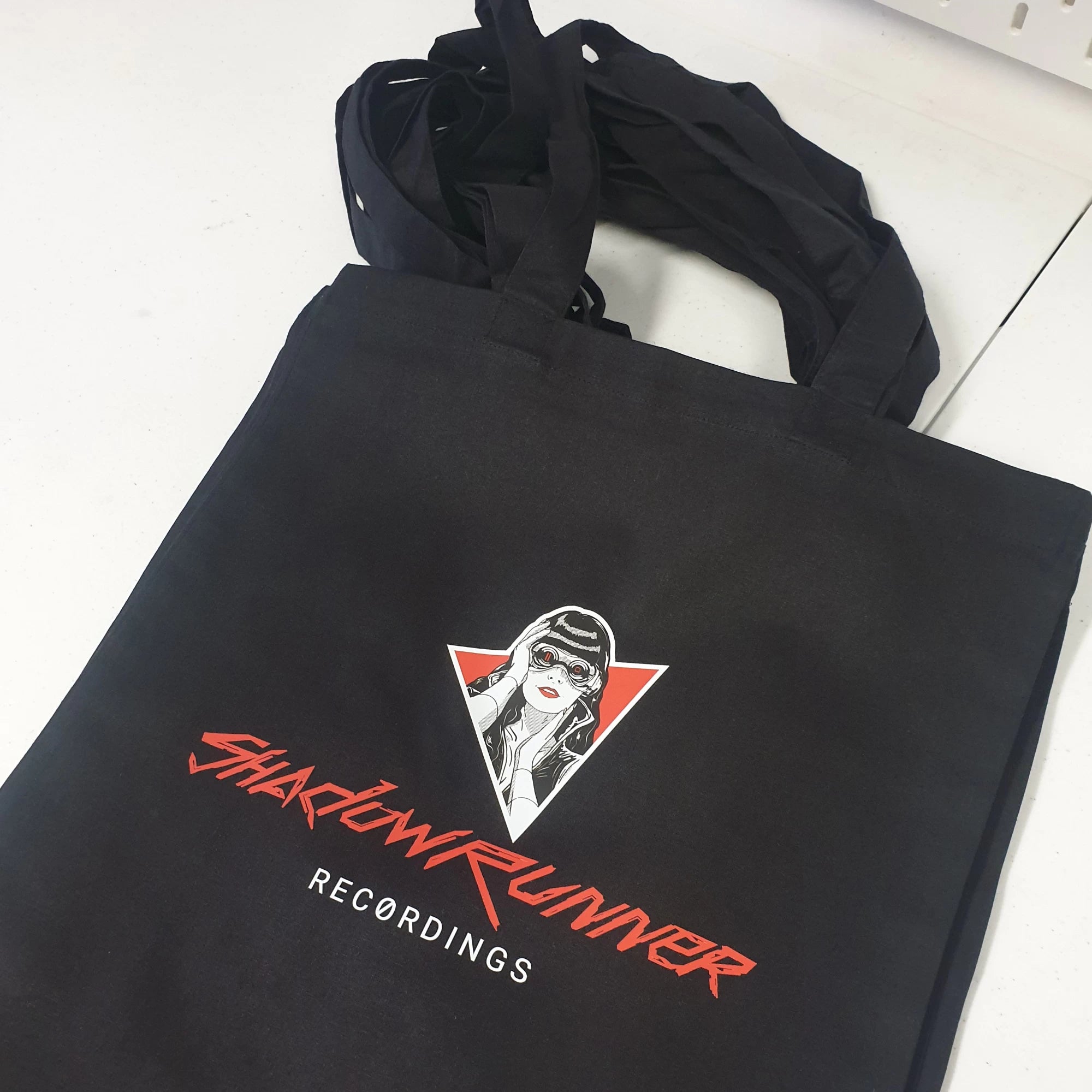 Black tote bag with 'Shadowrunner Recordings' logo on a white surface