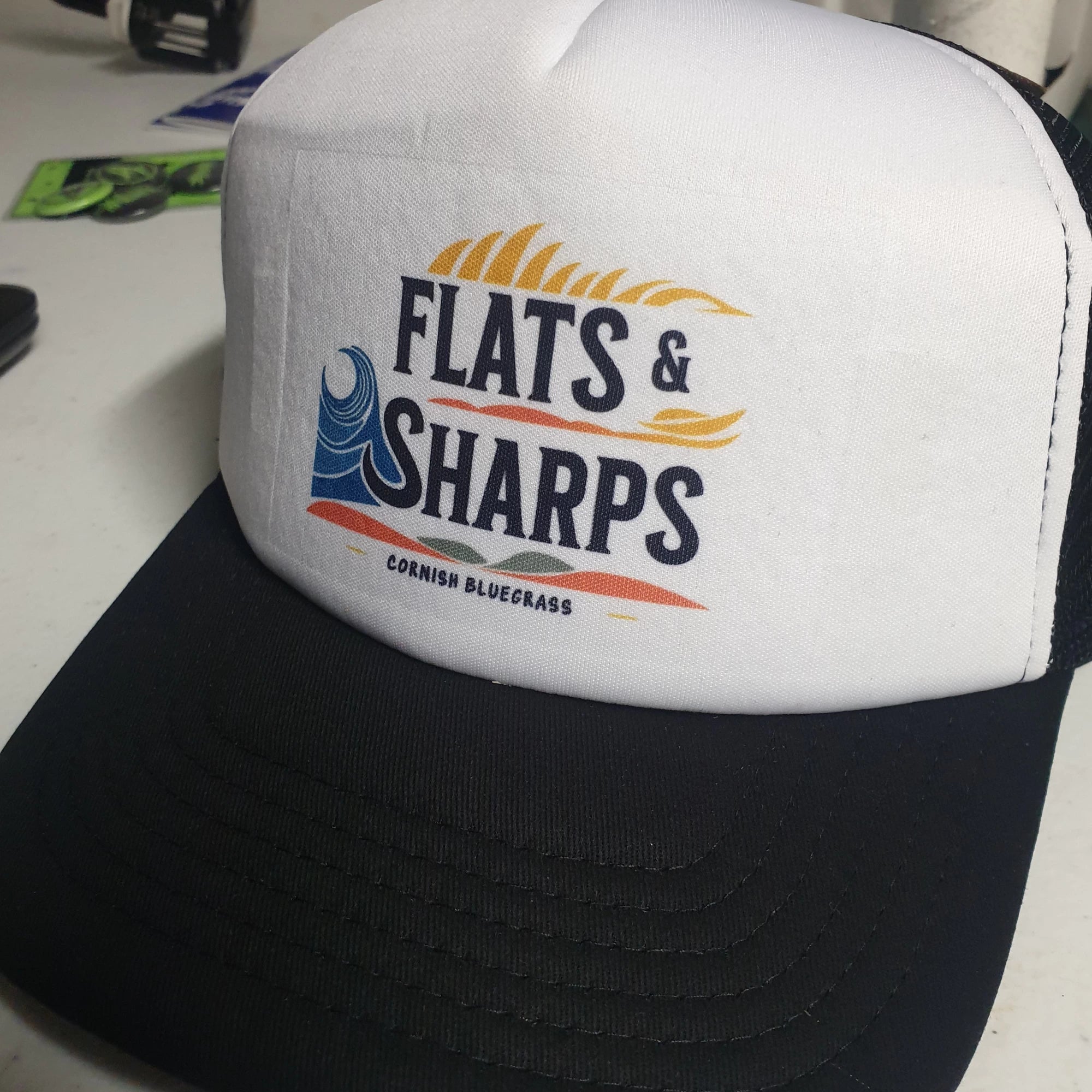 Black and white cap with 'Flats & Sharps' logo on a white surface