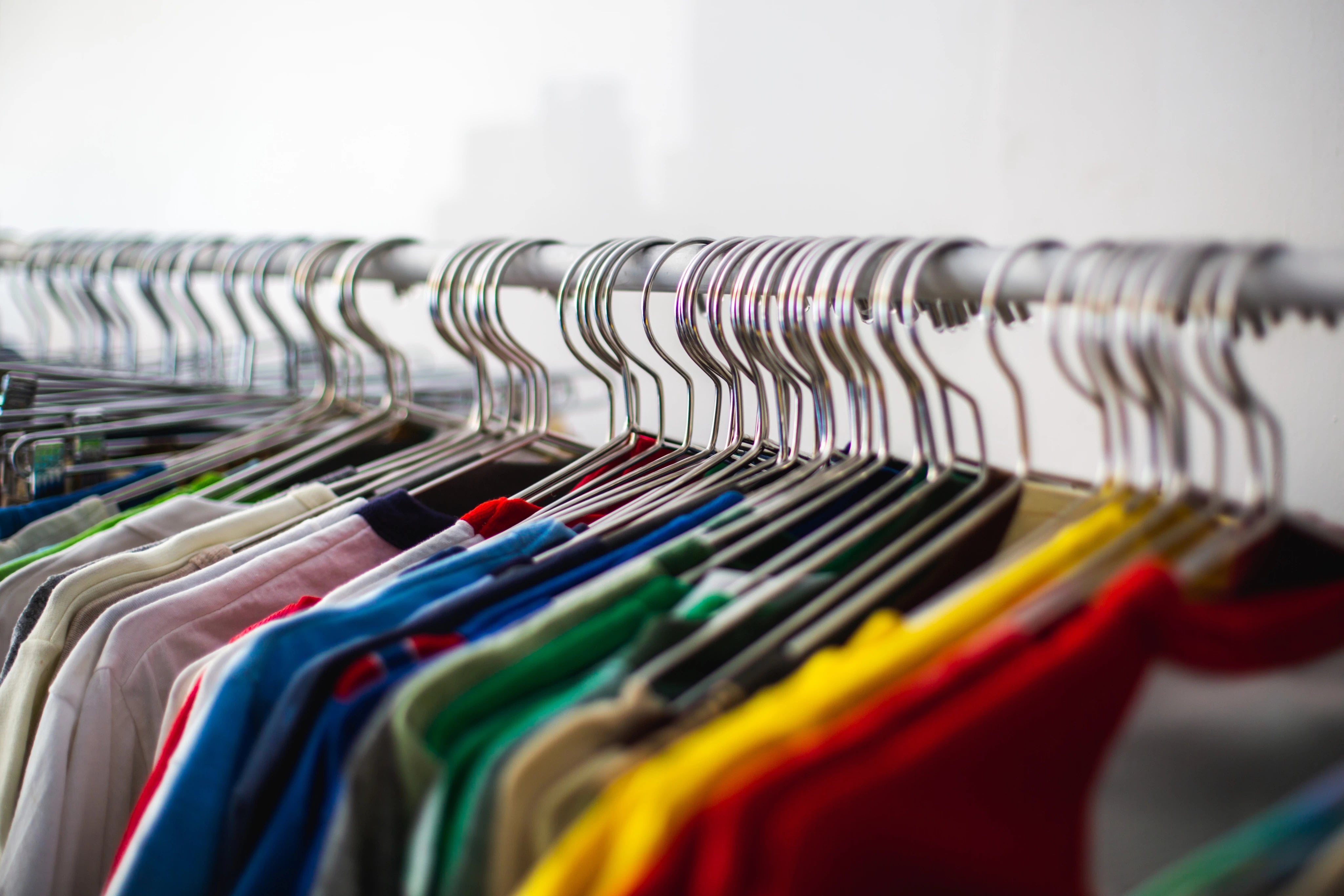 Multi-coloured T-shirts on a shop rack for opening a store with out of the box merch.